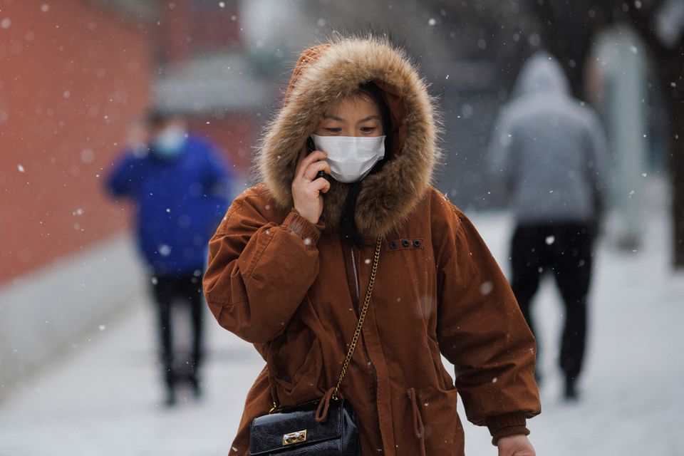 A person wears a face mask while walking on a snowy morning as the coronavirus disease (COVID-19) continues in Beijing, China, January 20, 2022. Photo: Reuters