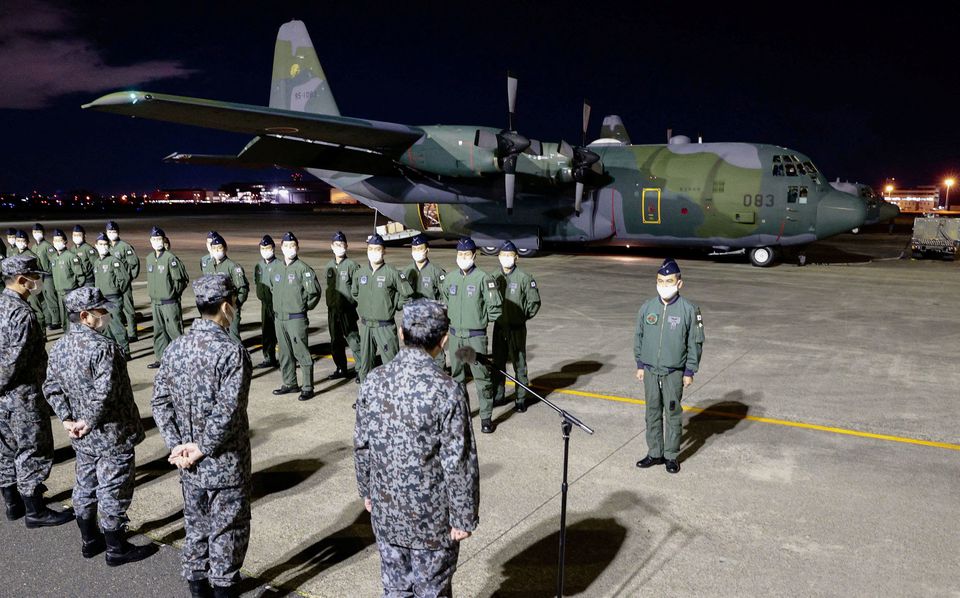 Japan Air Self-Defense Forces's members stand in front of their C-130 Hercules carrying relief supplies to be deployed to Tonga, to help out the country devastated by a nearby eruption and tsunami, before it's take off at Komaki air base in Komaki, Japan, January 20, 2022, in this photo taken by Kyodo. Photo: Kyodo/via REUTERS