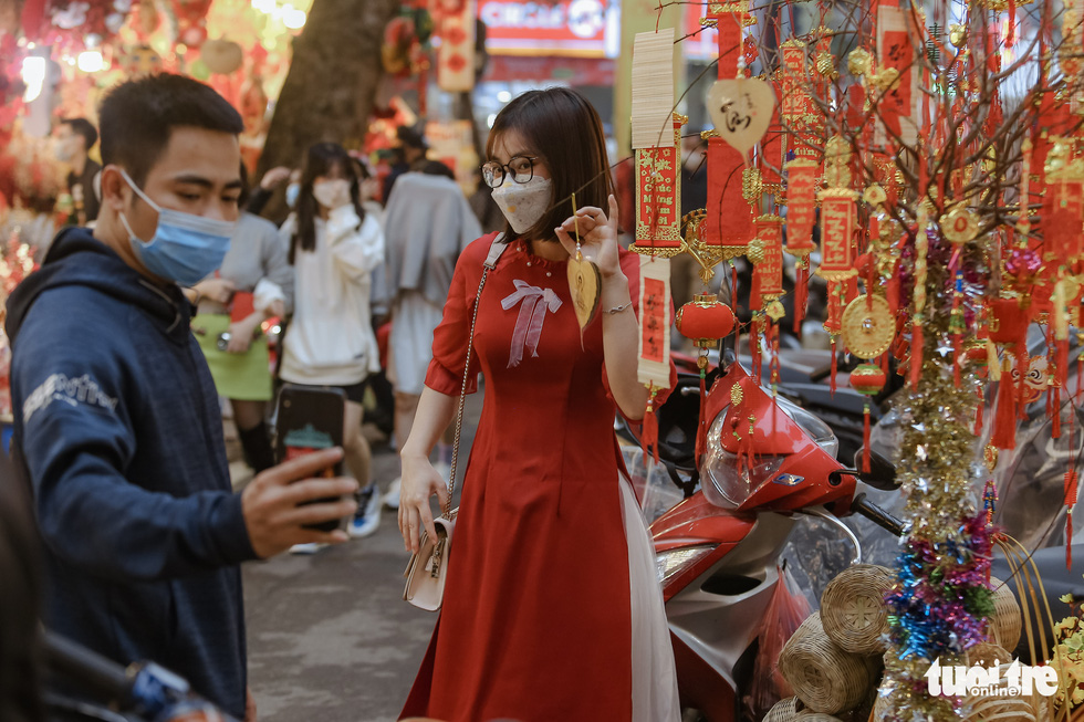 A young woman in the traditional Vietnamese 'ao dai’ poses for a photo at the Hang Luoc market in Hoan Kiem District, Hanoi. Photo: Ha Quan / Tuoi Tre