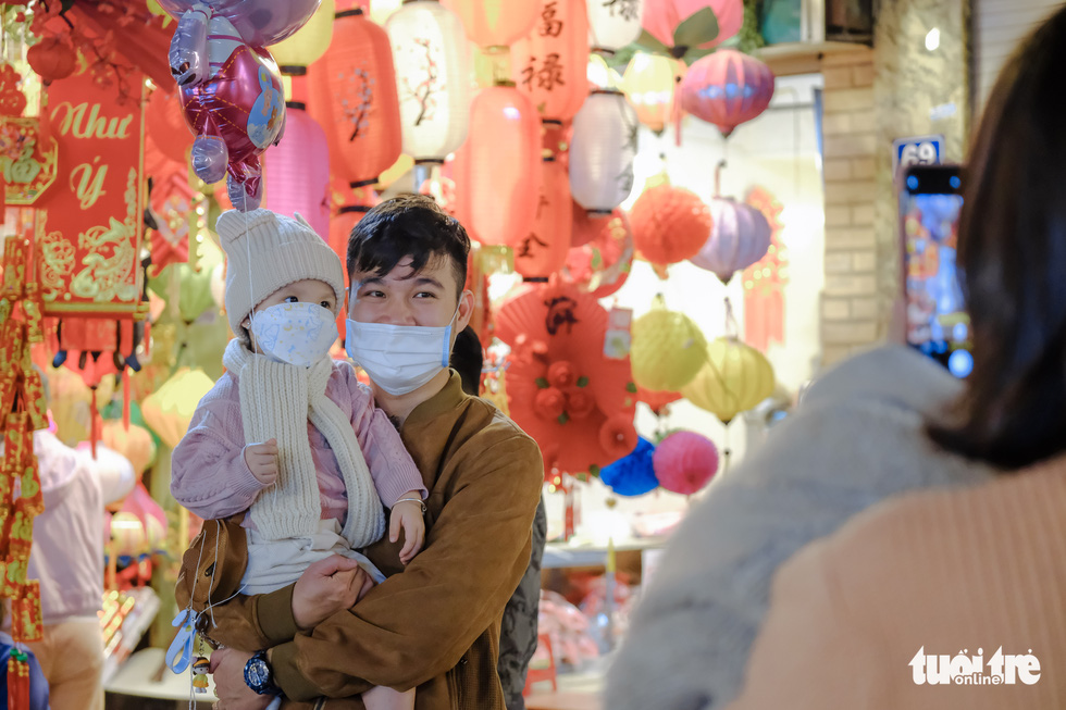 A man and his child pose for a photo with the Tet-themed background at the Hang Luoc market in Hoan Kiem District, Hanoi. Photo: Ha Quan / Tuoi Tre