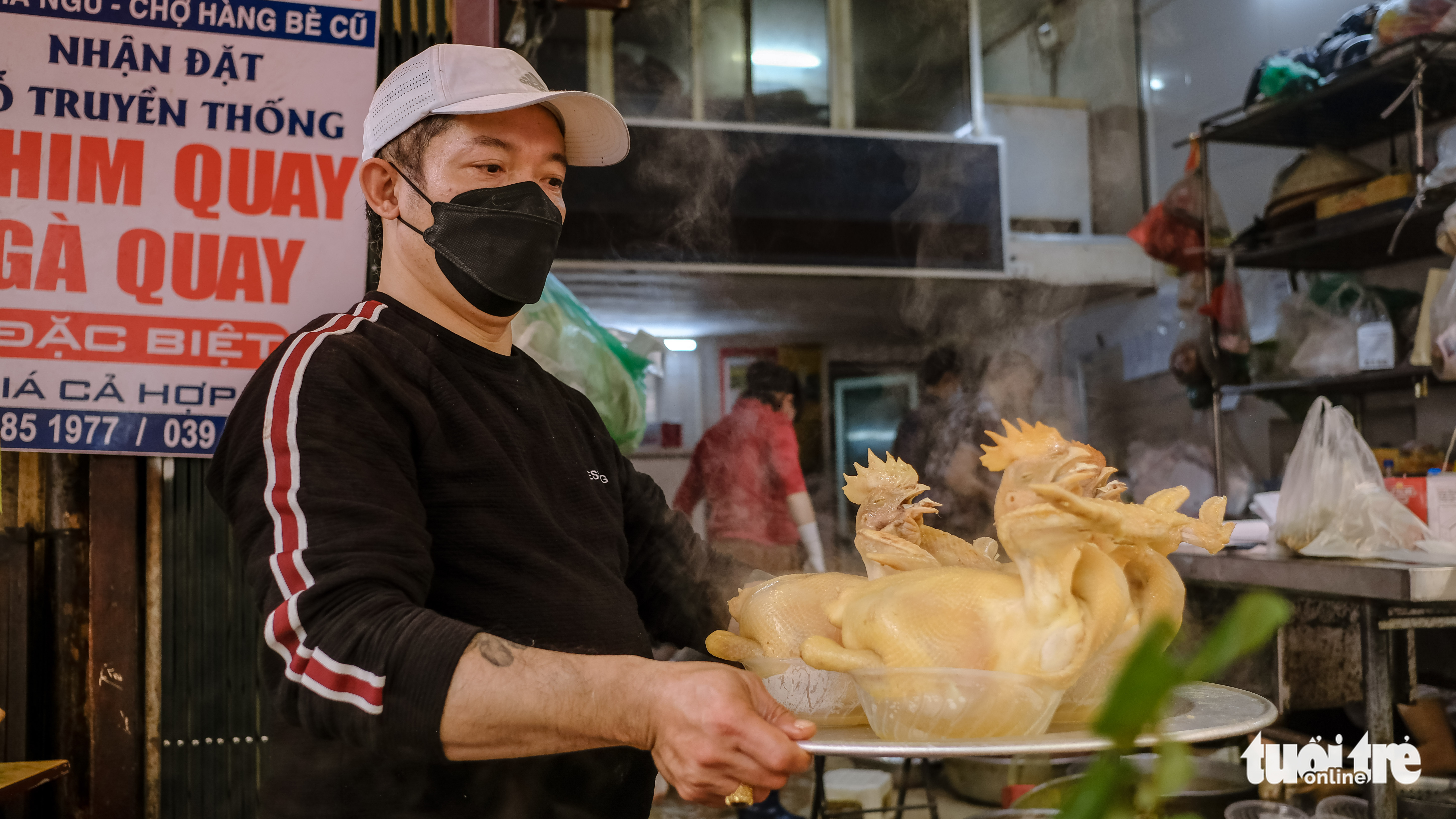 A man carries a tray of boiled chickens, a popular offering on the Kitchen God's farewell day in northern Vietnam, at a stall at Hang Be Market in Hoan Kiem District, Hanoi, January 25, 2022. Photo: Ha Quan / Tuoi Tre