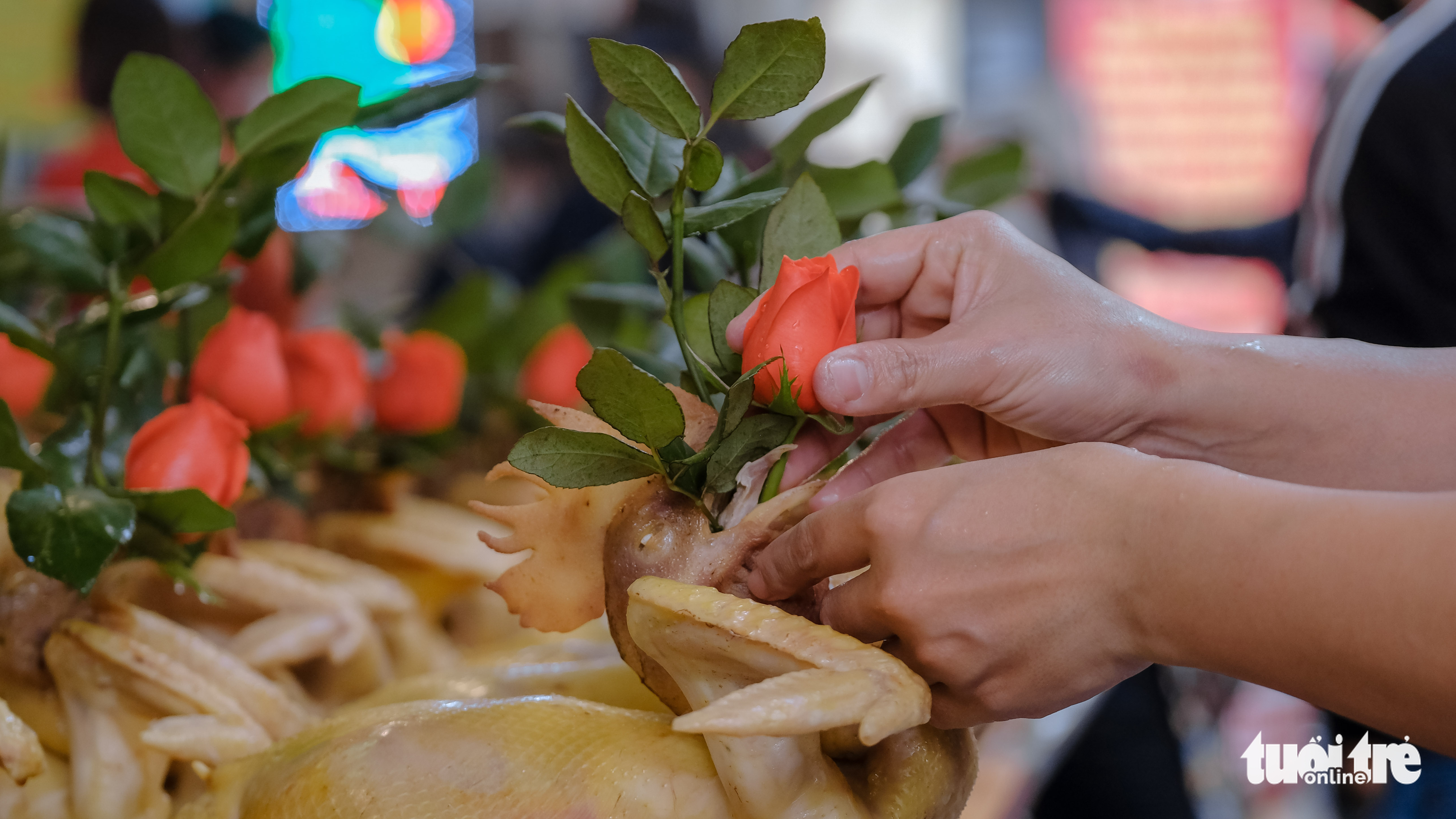 An attendant places a rose branch on the beak of a boiled chicken at a stall at Hang Be Market in Hoan Kiem District, Hanoi, January 25, 2022. Photo: Ha Quan / Tuoi Tre