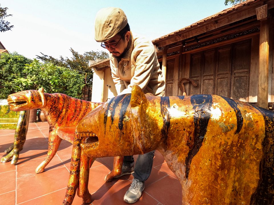 Nguyen Tan Phat stands in his yard with his Tiger carving works ahead of the Lunar New year in Hanoi, Vietnam January 18, 2022. Photo: Reuters