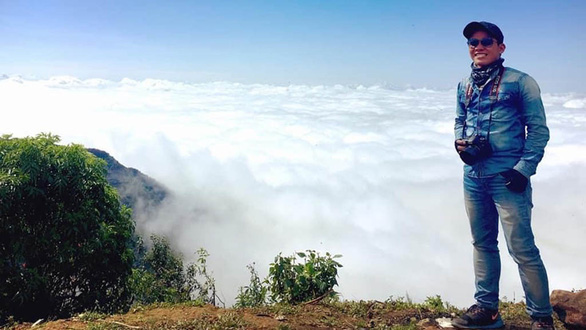 A tourist stops on a curb to take a photo of the cloudy scene on Hai Van Pass, Vietnam. Photo: Hoan Nguyen / Tuoi Tre