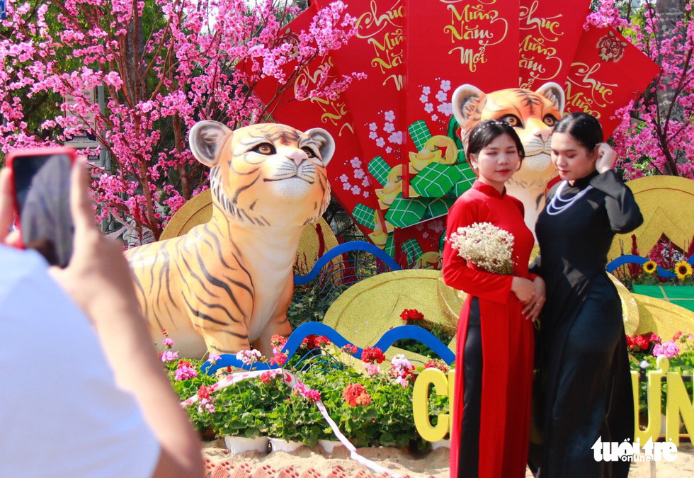 Two young women pose for a photo in front of a tiger statue while donning traditional Vietnamese 'ao dai' in Buon Ma Thuot City, Dak Lak Province, Vietnam. Photo: The The / Tuoi Tre