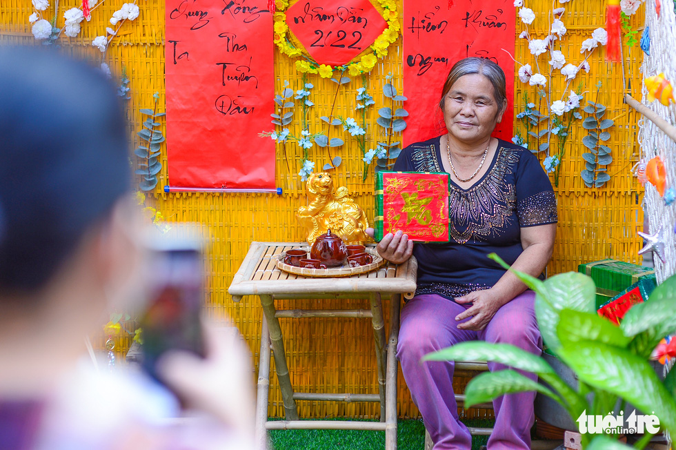 woman is posing for photos in front of a Tet-themed background.