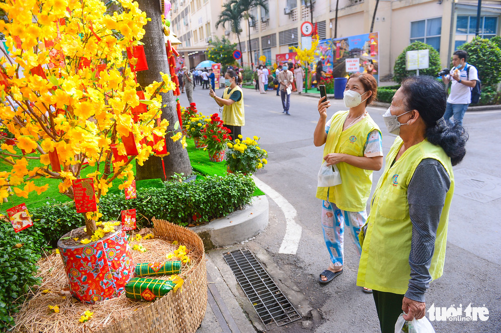 Patients’ caregivers take photos of the traditional Tet-themed background, glowing with blooming apricot blossoms.