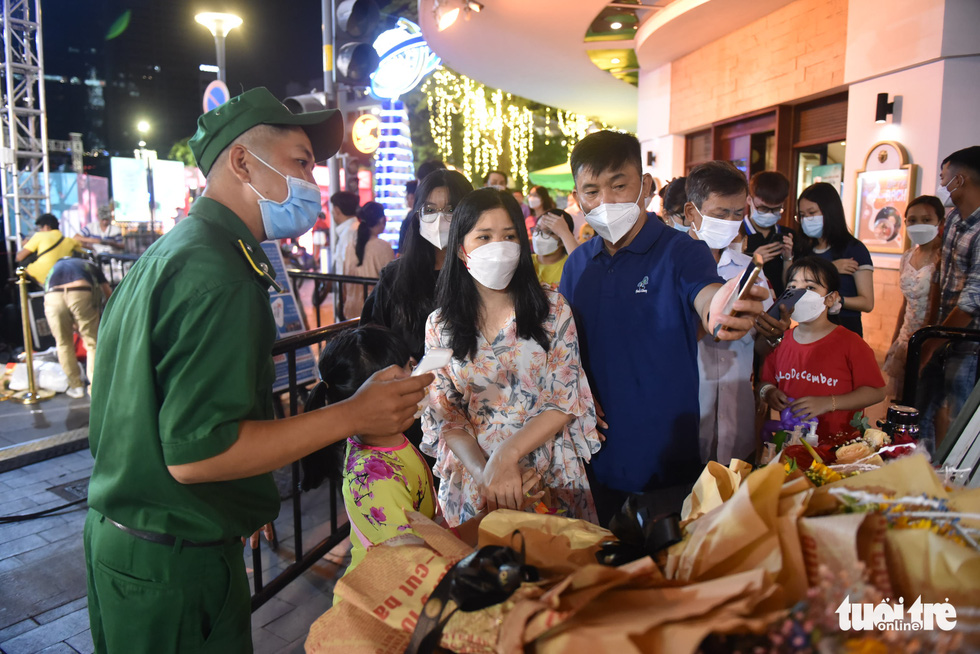 Security guard checks on certificates of COVID-19 vaccination from visitors on the Nguyen Hue Flower Street in District 1, Ho Chi Minh City, January 29, 2022. Photo: Tuoi Tre