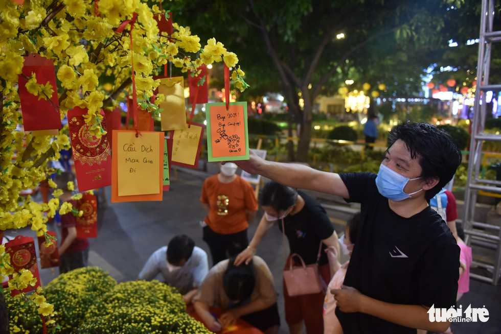 Visitors write down their prayers and hang them on the yellow apricot tree at the 2022 Lunar New Year's book street festival in District 1, Ho Chi Minh City, January 29, 2022. Photo: Tuoi Tre