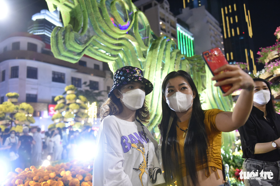 Two young women pose for a photo with the tiger mascot background on the Nguyen Hue Flower Street in District 1, Ho Chi Minh City, January 29, 2022. Photo: Tuoi Tre