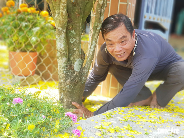 Vo Van Banh smiles for a photo while taking care of his yellow apricot blossom tree at his house in the Mekong Delta province of An Giang’s Thoai Son District on February 3, 2022. Photo: Ngoc Khai / Tuoi Tre