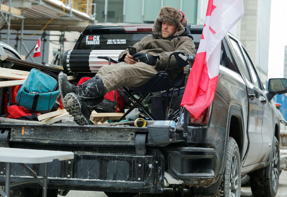 A man relaxes in his pickup truck as truckers and supporters continue to protest against the COVID-19 vaccine mandates in Ottawa, Ontario, Canada, February 6, 2022. Photo: Reuters