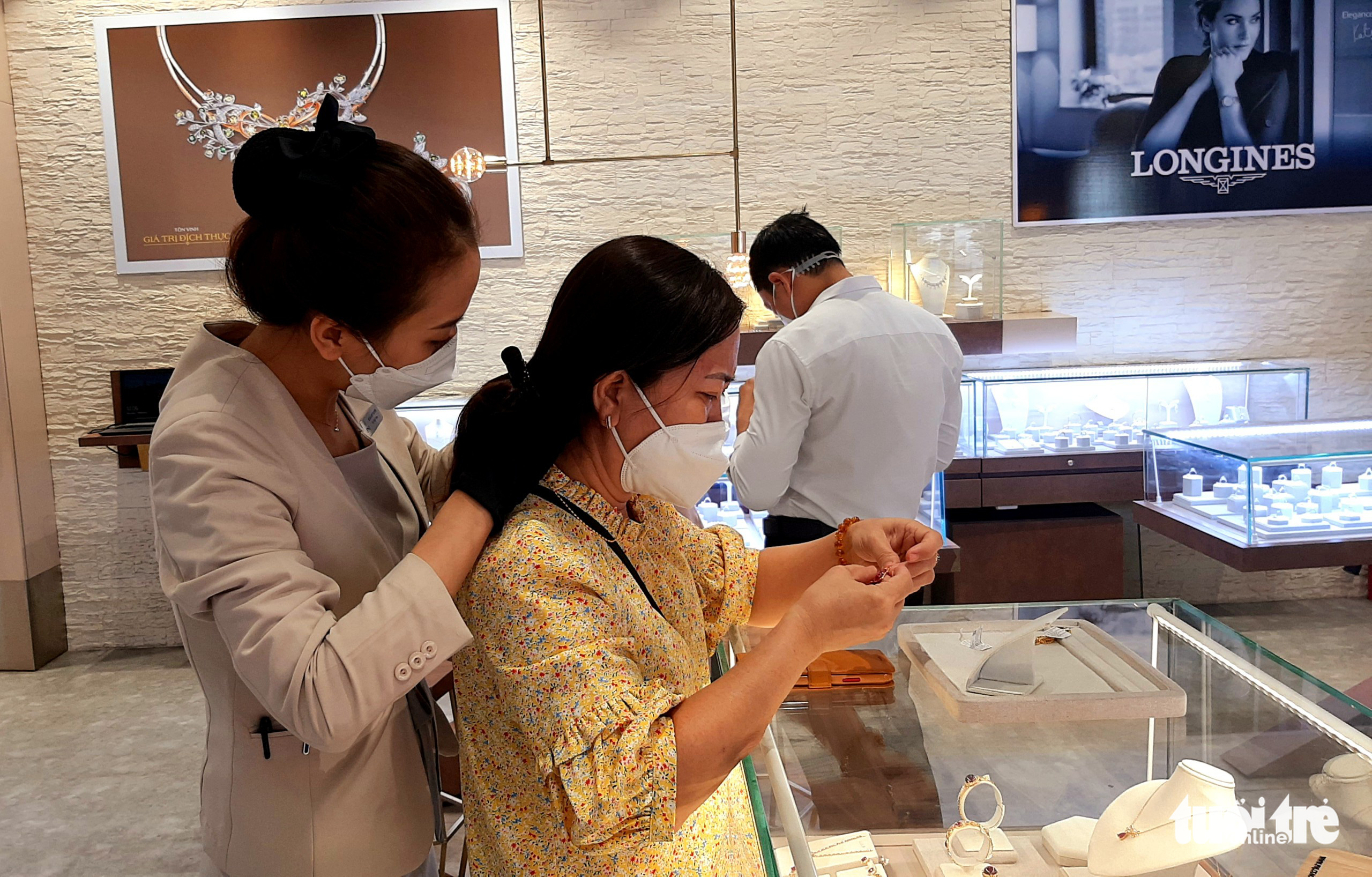 An employee helps a customer try on a gold necklace at a jewelry shop in Ho Chi Minh City on February 8, 2022. Photo: Cong Trieu / Tuoi Tre