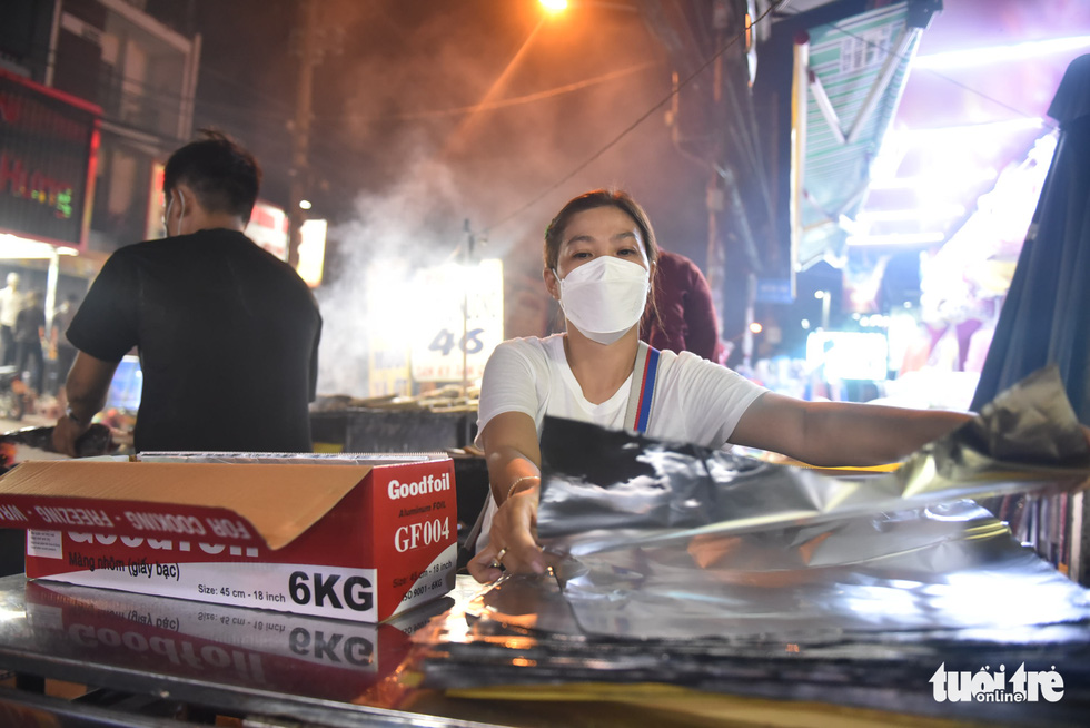 A woman prepares aluminum foils prior to grilling the snakehead fish at a shop in Tan Phu District, Ho Chi Minh City, February 9, 2022. Photo: Ngoc Phuong / Tuoi Tre