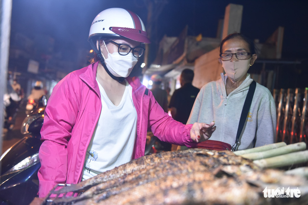 A woman chooses her grilled snakehead fish at a shop in Tan Phu District, Ho Chi Minh City, February 9, 2022, to prepare for the God of Wealth Day. Photo: Ngoc Phuong / Tuoi Tre
