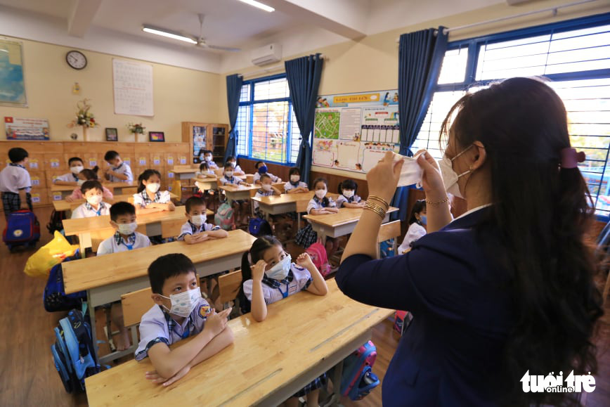 This image shows a teacher guiding students on how to properly wear a face mask at Le Duc Tho Elementary School. Photo: Nhat Thinh / Tuoi Tre