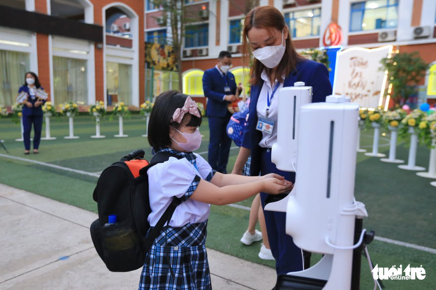 A student is seen having her hands disinfected before entering her classroom at Le Duc Tho Primary School. Photo: Nhat Thinh / Tuoi Tre