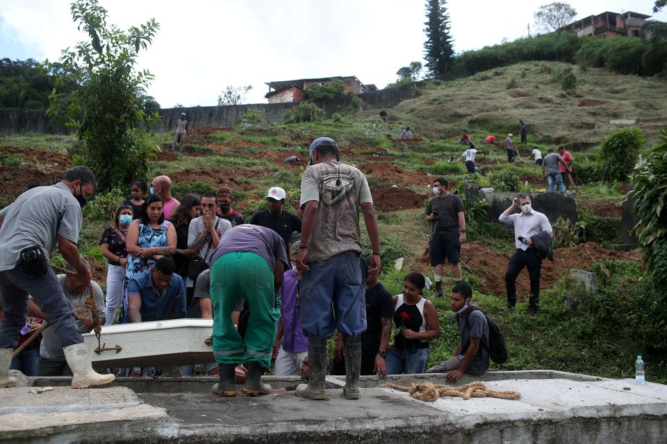 Relatives and friends react as a coffin is lowered during the burial of Debora Listenberg, 22 and her kids Heloise, 2 and Gustavo, 5 after pouring rains caused flooding in Petropolis, Brazil February 17, 2022. Photo: Reuters