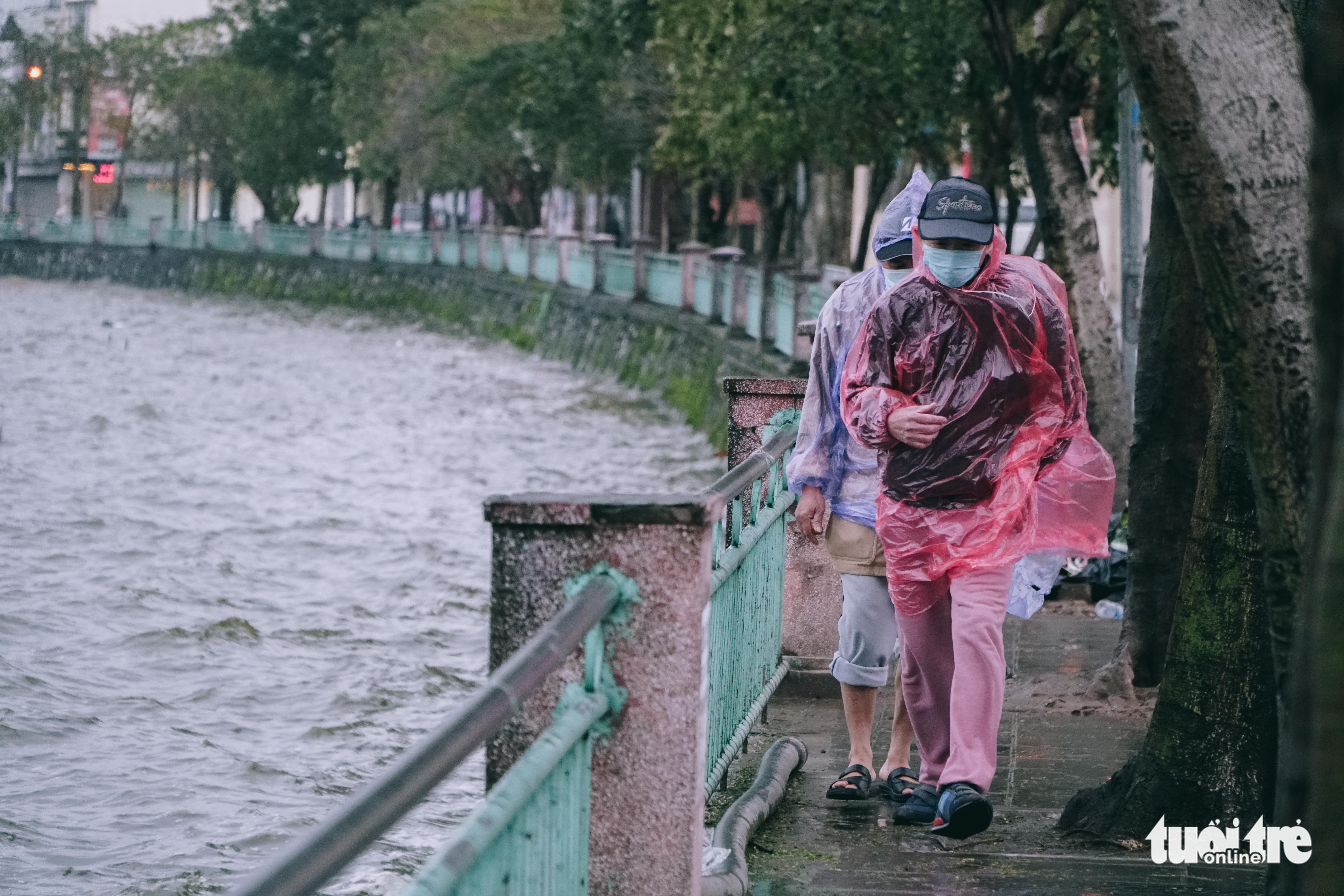 People put on rain coats as they have a walk in cold and rainy weather in Hanoi, February 19, 2022. Photo: Pham Tuan / Tuoi Tre