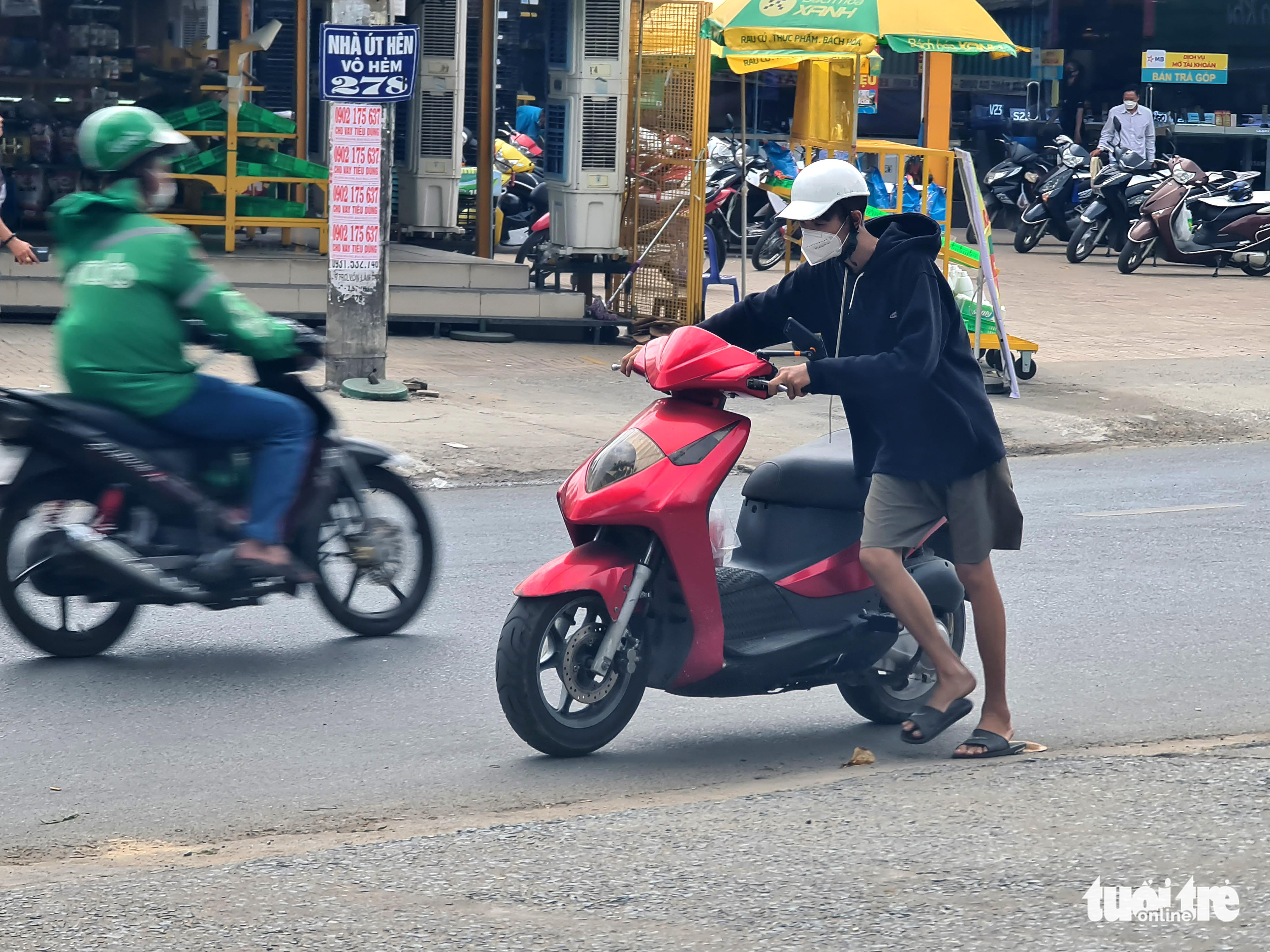A resident pushes his motorbike after it runs out of gasoline in Go Vap District, Ho Chi Minh City, February 20, 2022. Photo: Ngoc Hien / Tuoi Tre