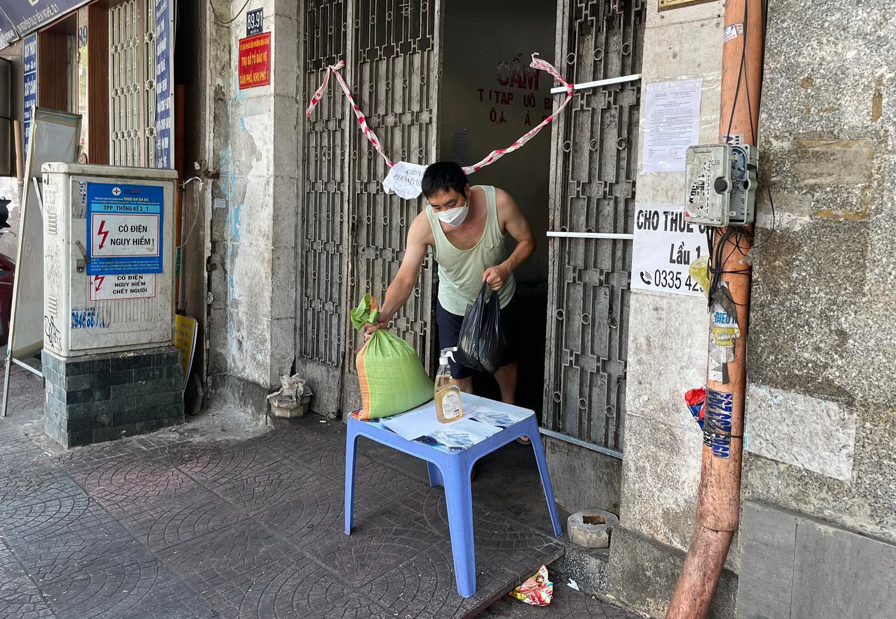 A resident receives goods at the apartment sealed off due to a new COVID-19 cluster at 89-91 Nguyen Du Street in District 1, Ho Chi Minh City, February 21, 2022. Photo: Le Phan / Tuoi Tre