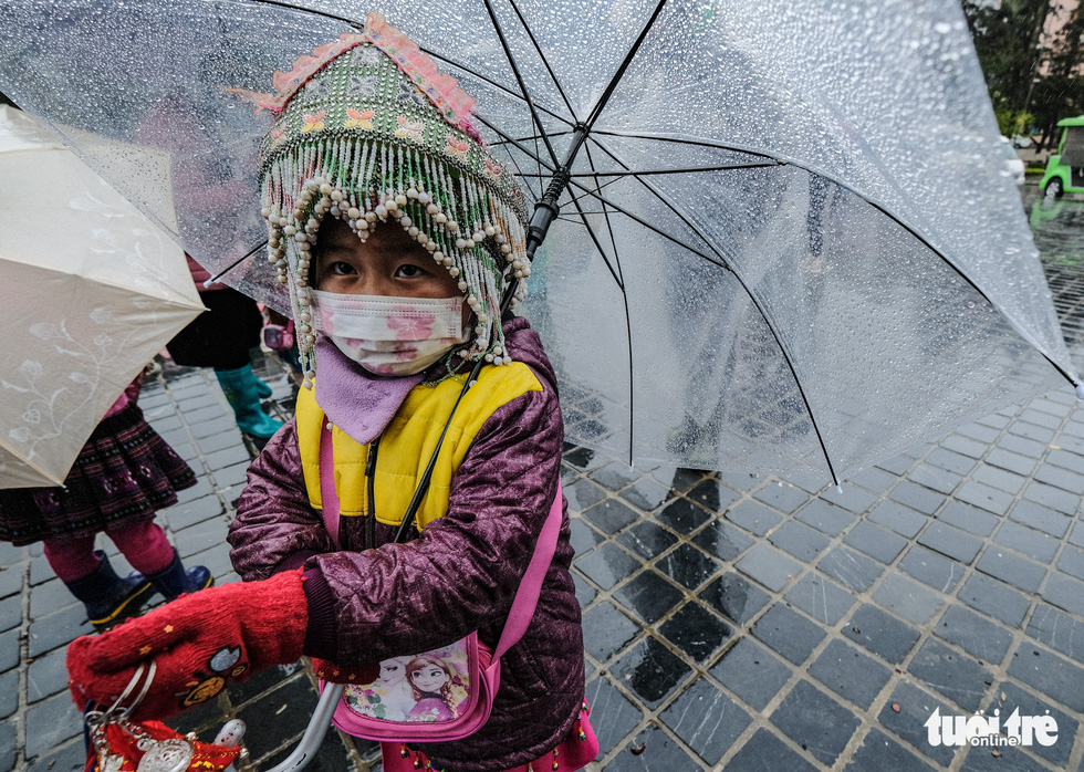 A child street vendor is seen with some key chains on her hands on the way to sell such items in the cold rain in Sa Pa Town.