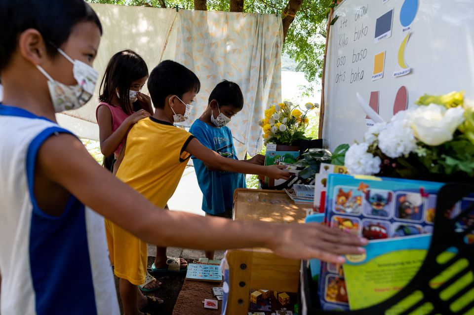 Children select books from the makeshift trolley which serves as a mobile library, near the railroad, in Tagkawayan, Quezon Province, Philippines, February 15, 2022. Photo: Reuters