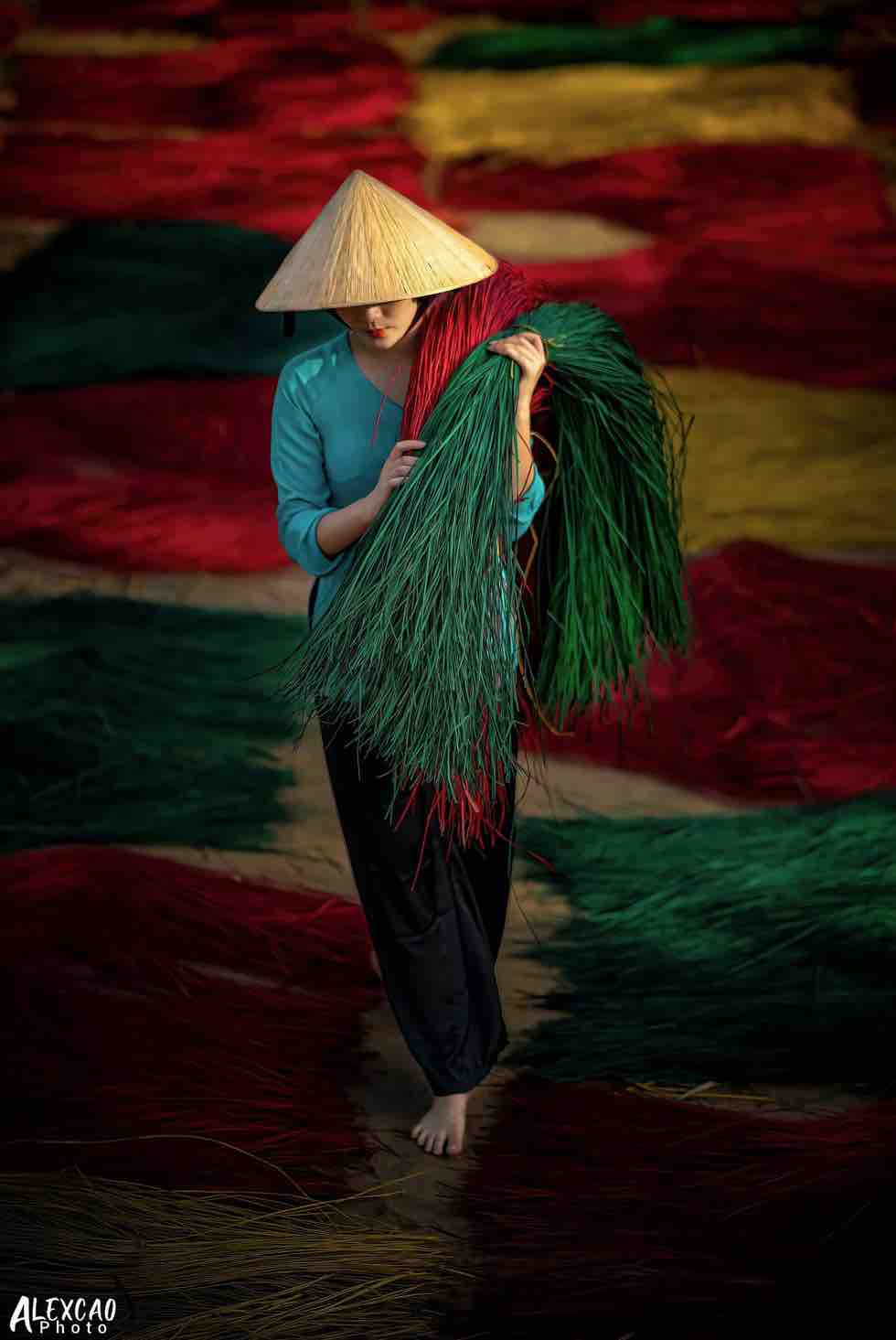 Alex Cao’s photo 'Nghe lam chieu' (Straw Mat Making) captures a moment of an artisan carrying colored sedges, the material used to make straw mats, on her shoulder. Photo: Alex Cao
