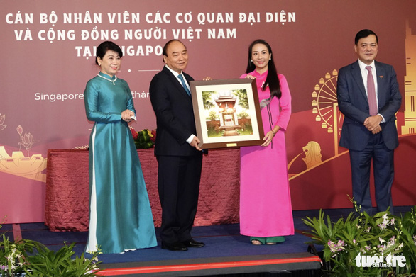 Vietnamese State President Nguyen Xuan Phuc (second left) and his spouse (first left) are seen presenting a souvenir to a representative of the Vietnamese community in Singapore on February 26, 2022. Photo: Vien Su / Tuoi Tre