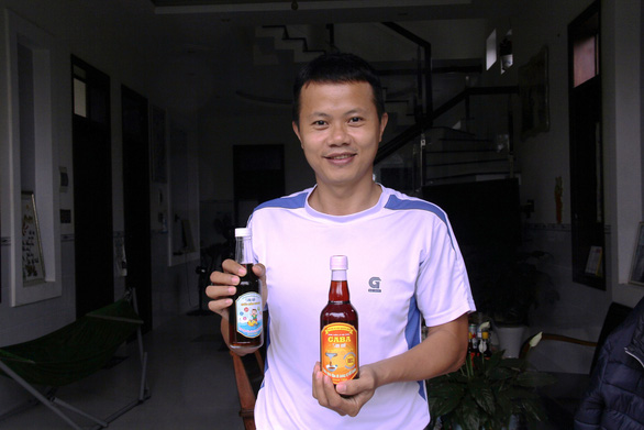 Tran Anh Vy, PhD poses with his two new lines of fish sauce products, GABA Son My and fish sauce for children. Photo: Tran Mai/ Tuoi Tre