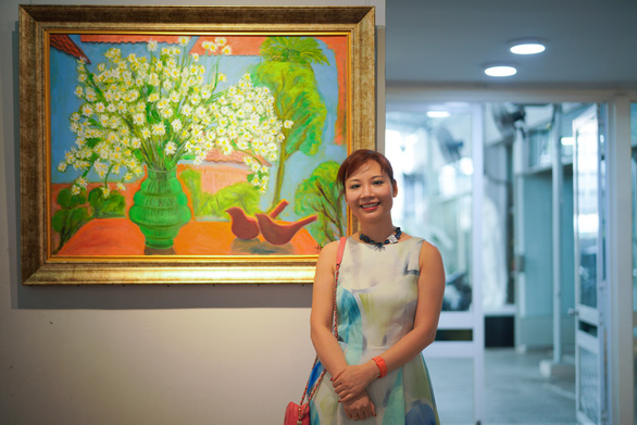 Tran Thao Hien stands next to her oil painting ‘Vao mua cuc hoa mi’ (When the daisies bloom). Her ‘green dream’ is kept alive in the beauty of nature, where birds enjoy a peaceful spring filled with love and light.