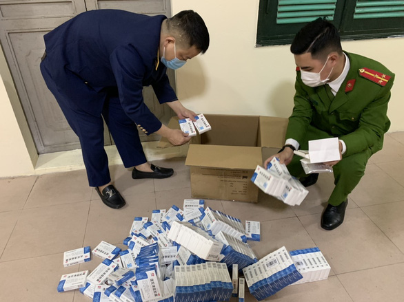 This photo shows the boxes of “Lianhua Qingwen Jiaonang” drug, without documentations on the origin, being examined by market surveillance officers in Hanoi on March 3, 2022. Photo: Vietnam Directorate of Market Surveillance