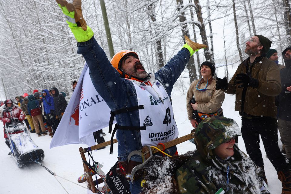 Matt Paveglio tossing candy to onlookers during the ceremonial start of the 50th Iditarod Trail Sled Dog Race in Anchorage, Alaska, U.S. March 5, 2022. Photo: Reuters