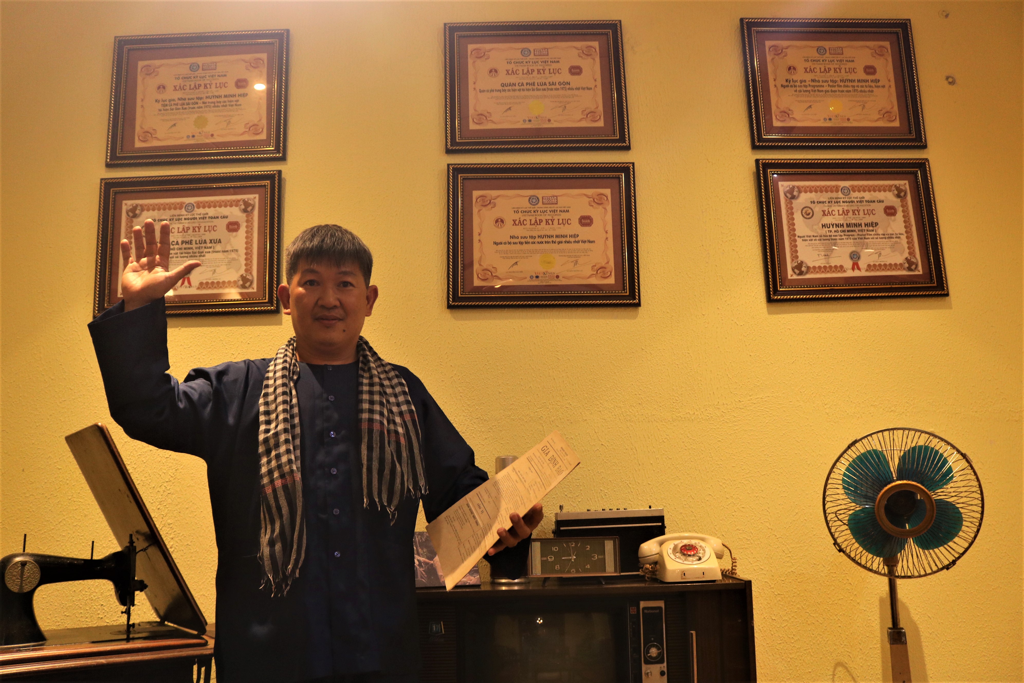 Huynh Minh Hiep poses with certificates recognizing the depth of his antique collection at Lua Sai Gon café in Phu Nhuan District, Ho Chi Minh City. Photo: Hoang An / Tuoi Tre News