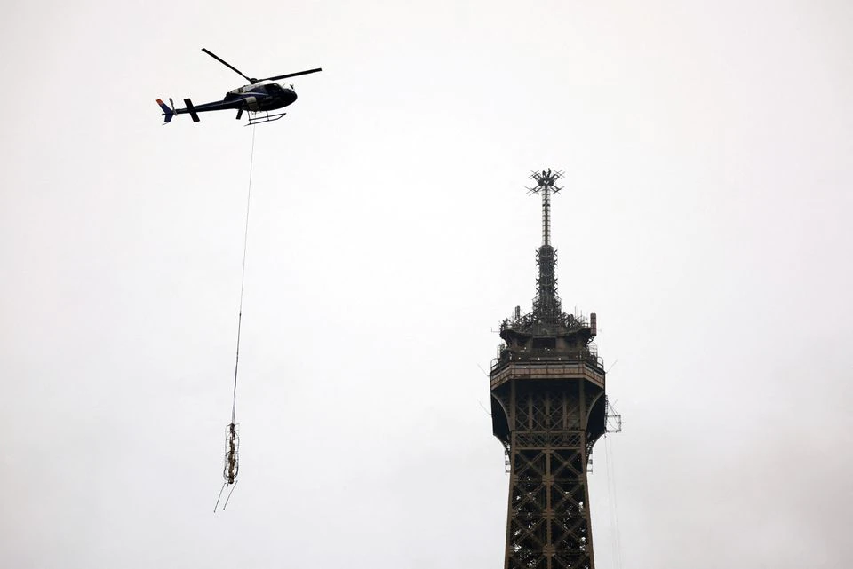 A helicopter flies next to the Eiffel Tower to install a new telecom transmission TDF (TeleDiffusion de France) antenna on its top, in Paris, France, March 15, 2022. Photo: Reuters