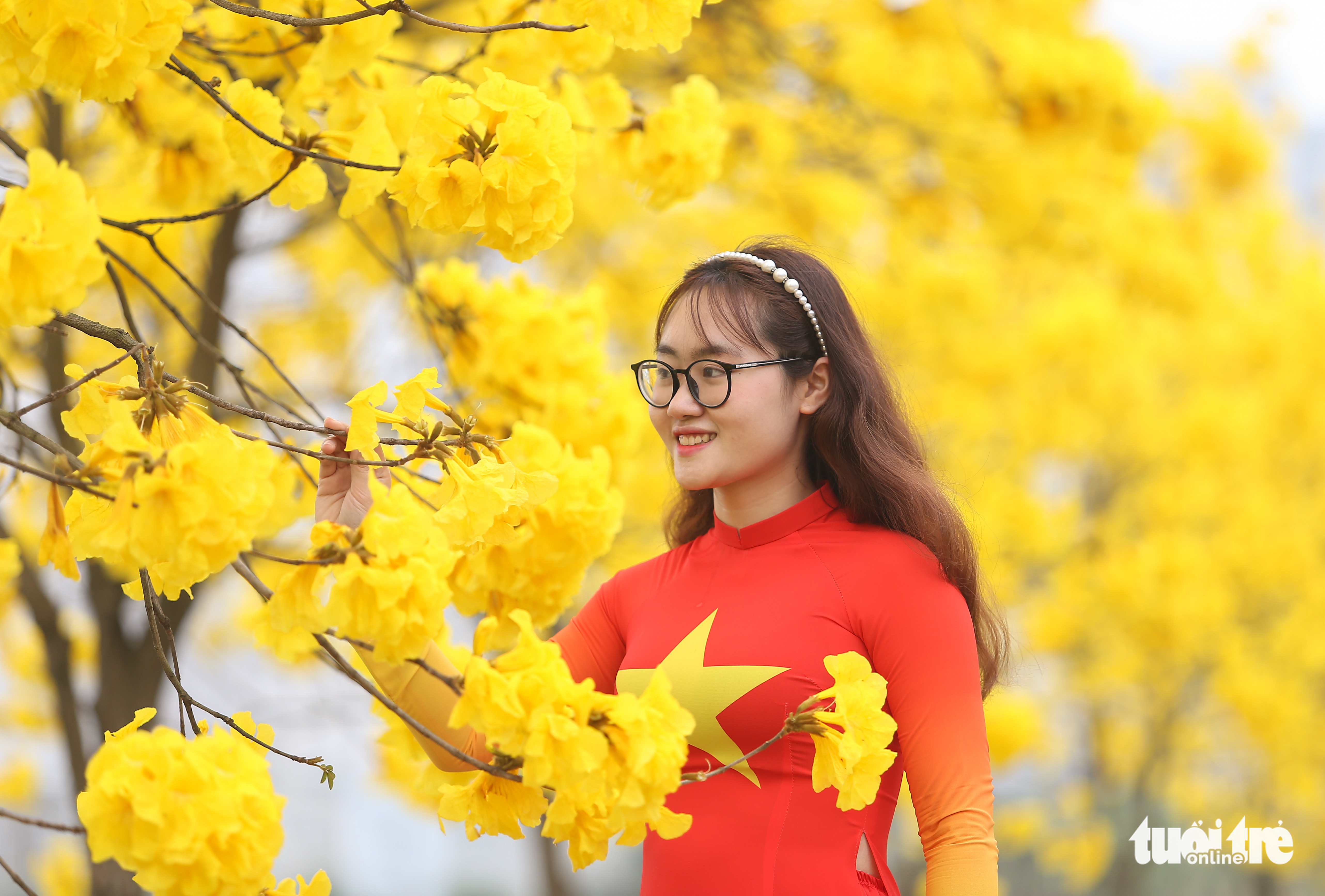 <em>A woman poses for a photo next to a Caribbean trumpet tree at the ParkCity urban area in Ha Dong District, Hanoi. Photo: </em>Ha Quan / Tuoi Tre