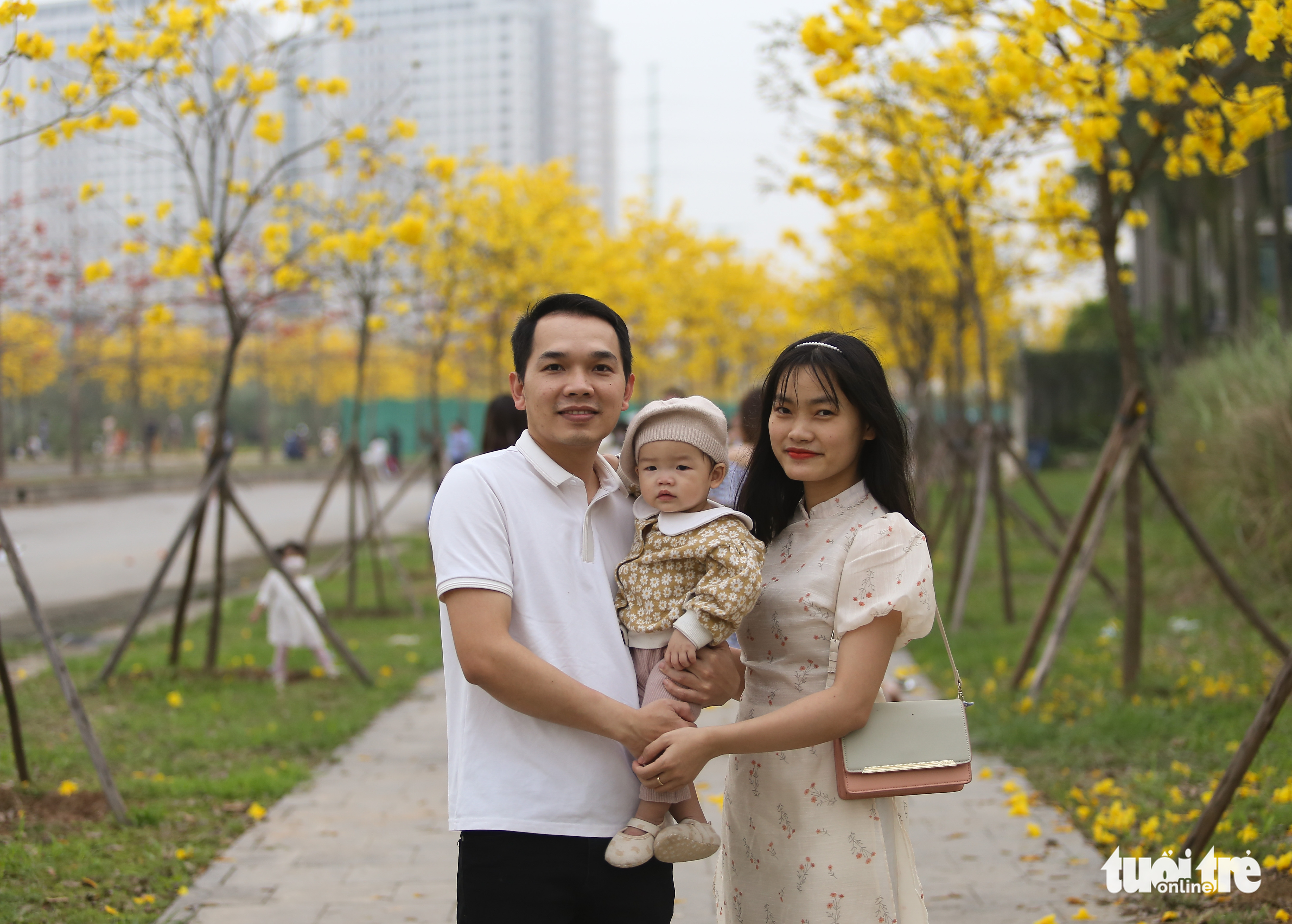 <em>A family poses for a photo on a Caribbean trumpet tree street at the ParkCity urban area in Ha Dong District, Hanoi. Photo: </em>Ha Quan / Tuoi Tre
