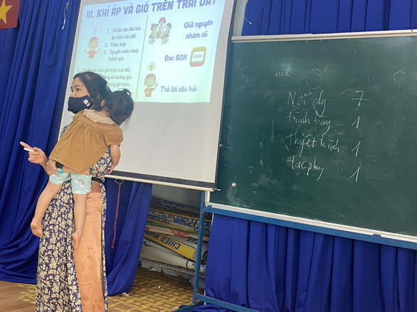 Teacher carries child while teaching class in Ho Chi Minh City