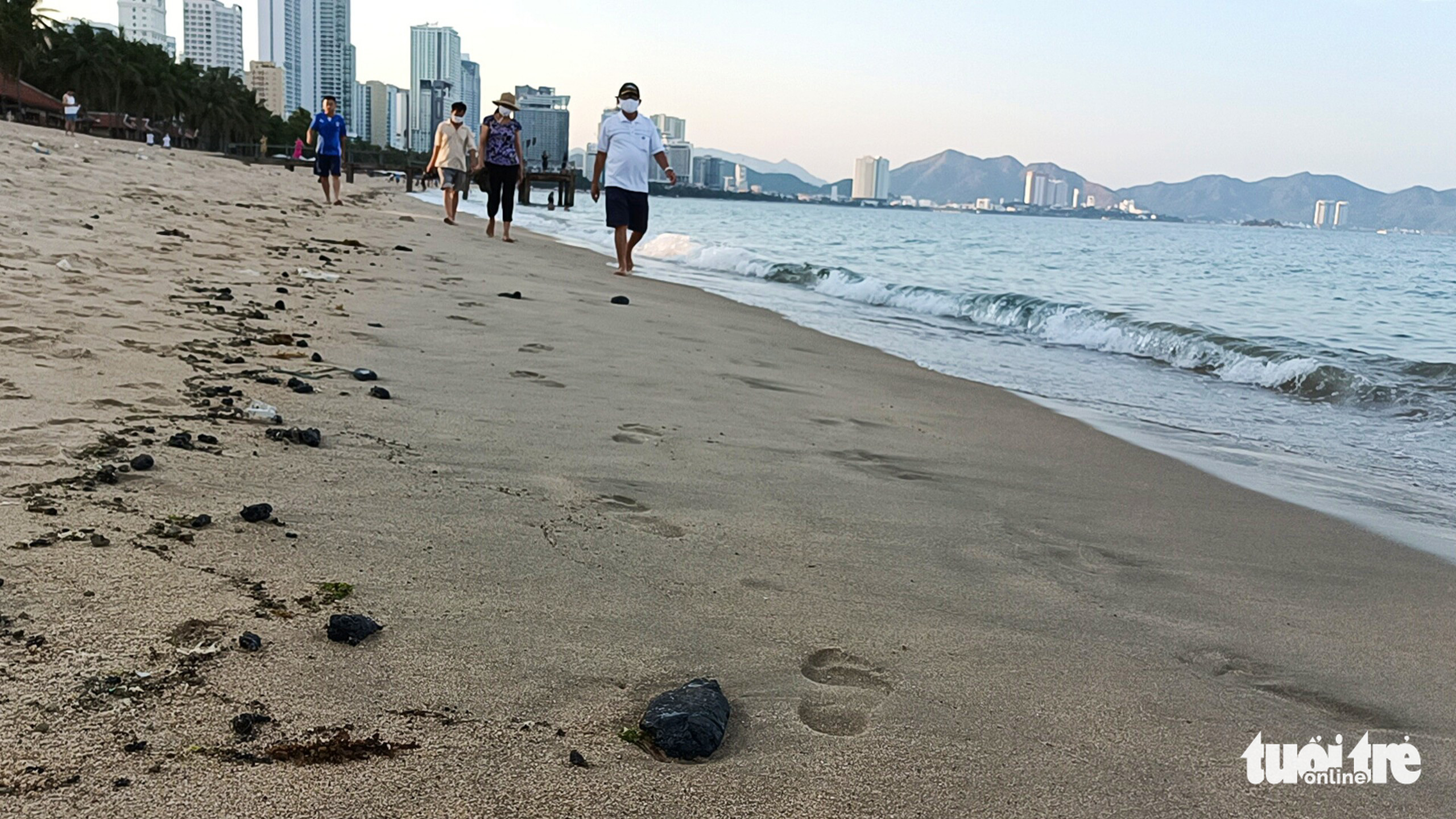 People walk near crude oil masses of unknown origins on a beach in Nha Trang City, Khanh Hoa Province, Vietnam, March 17, 2022. Photo: Minh Chien / Tuoi Tre