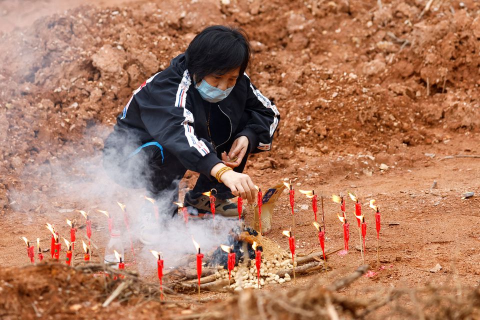 A woman surnamed Liang, 60, takes part in a Buddhist ceremony in honor of the victims in a field close to the entrance of Simen village, near the site where a China Eastern Airlines Boeing 737-800 plane flying from Kunming to Guangzhou crashed, in Wuzhou, Guangxi Zhuang Autonomous Region, China March 22, 2022. Photo: REUTERS