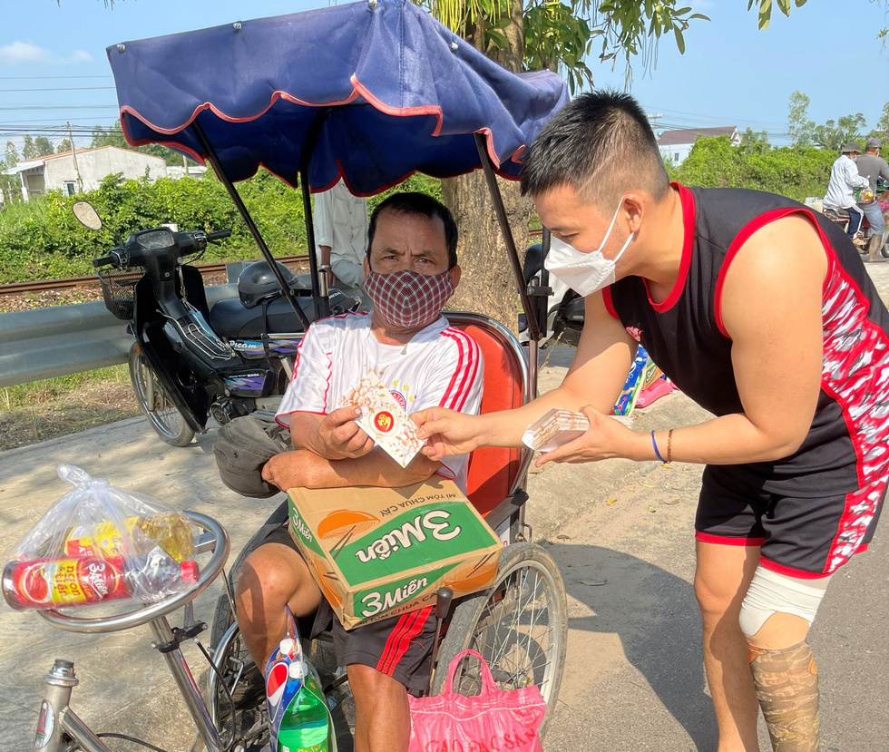 Nguyen Van Luu (right) gifts a lottery ticket peddler whose livelihood was hurt by COVID-19 outbreaks in Binh Dinh Province during the 2022 Tet (Lunar New Year) holiday.