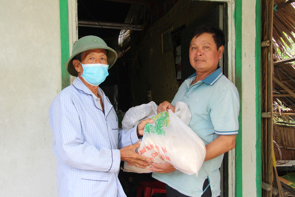 Nguyen Van Le (left) gifts the less better-off rice and other necessities.