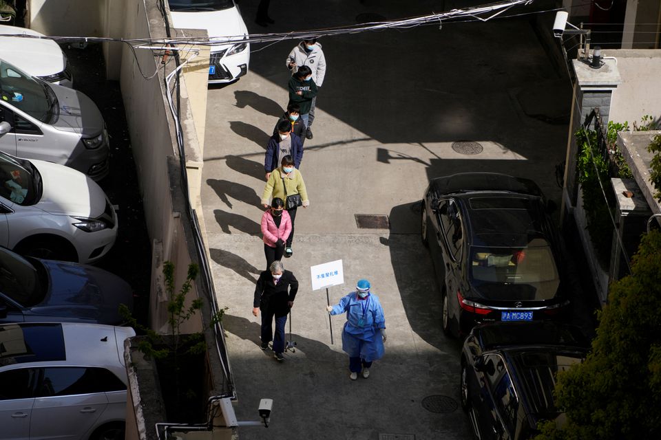 A worker in a protective suit directs residents lining up for nucleic acid testing during the second stage of a two-stage lockdown to curb the spread of the coronavirus disease (COVID-19) in Shanghai, China April 4, 2022. Photo: Reuters