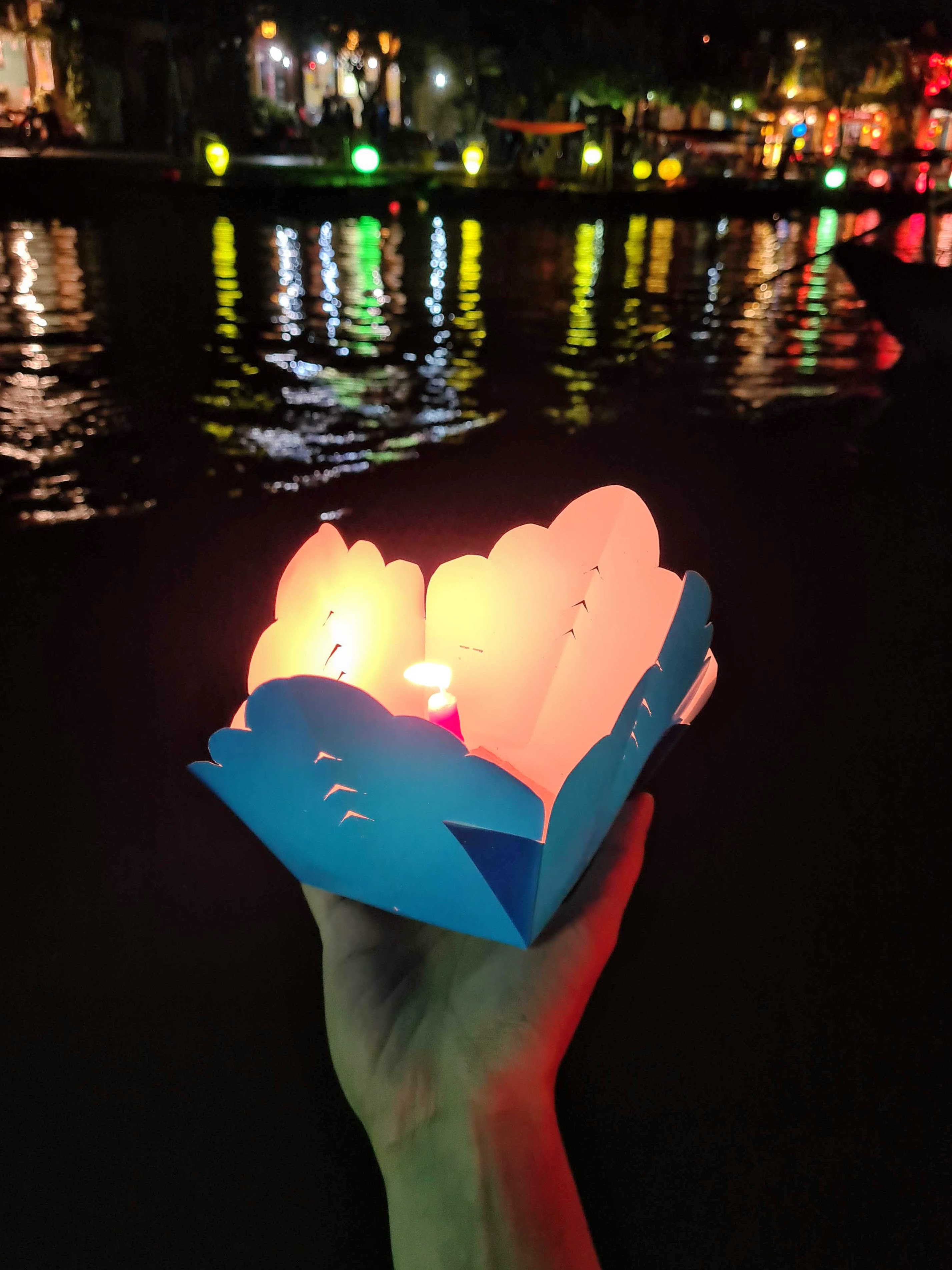 A tourist holds a candle-lit lantern while taking a boat ride along the Hoai River in Hoi An Ancient Town, Quang Nam Province, Vietnam. Photo taken on April 3, 2022. Photo: Duy Khang / Tuoi Tre