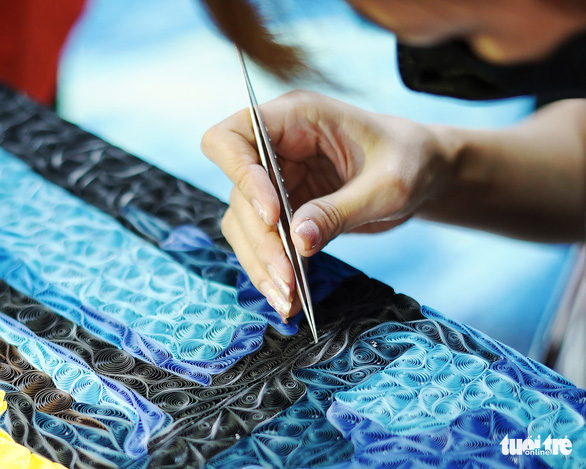 An artisan meticulously inserts paper in tight spaces using tweezer. Photo: N.H. / Tuoi Tre