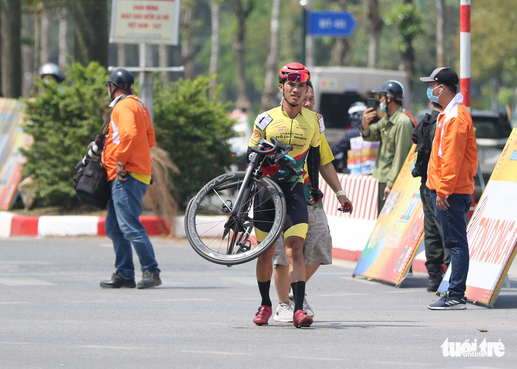 A cyclist carries his bike to the finish line following the accident in the fifth stage of the Ho Chi Minh City TV (HTV) Cup tournament, April 9, 2022. Photo: T.P. / Tuoi Tre
