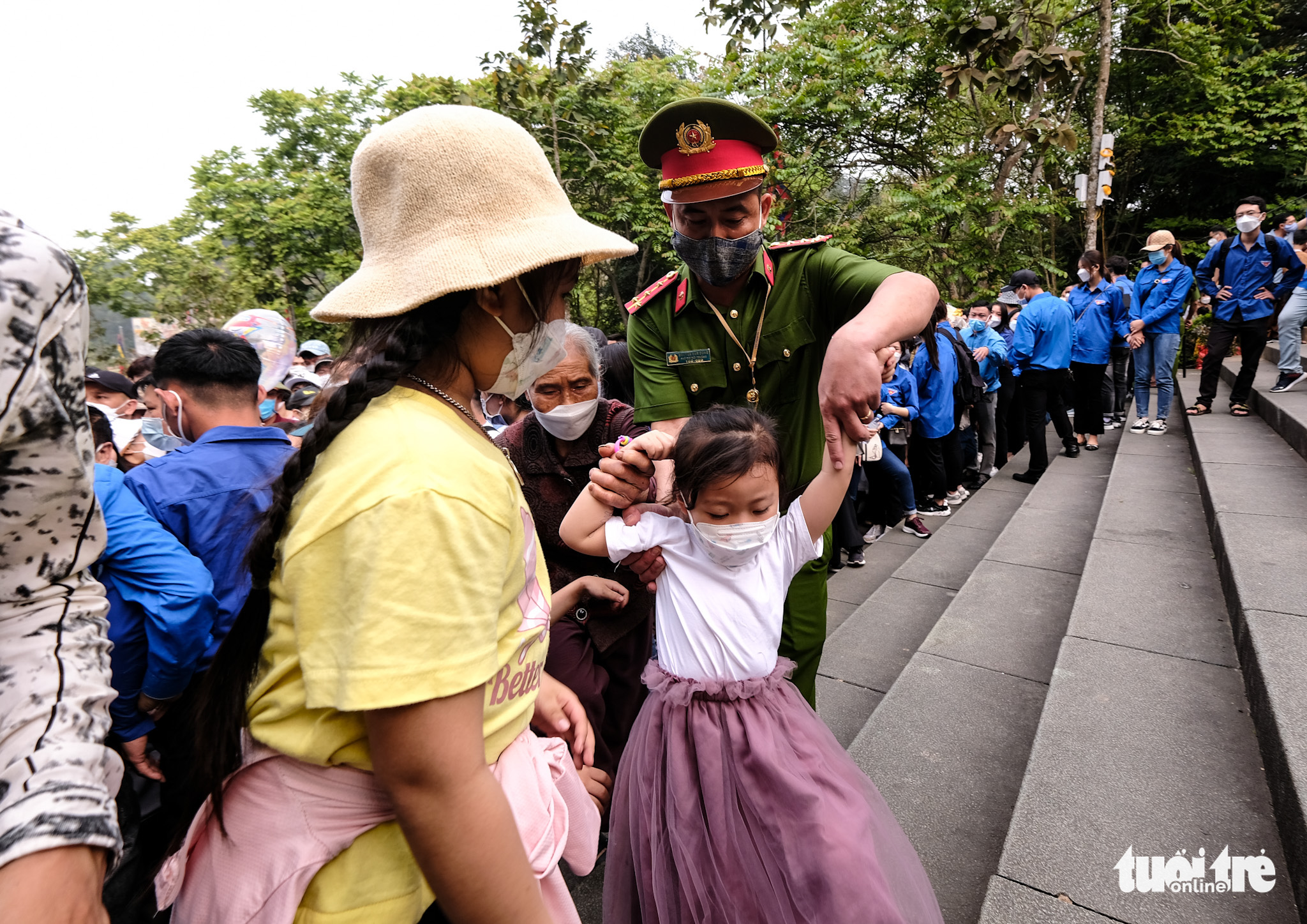 An officer helps a young girl on her way to the Hung King Temples in Phu Tho Province, Vietnam, April 10, 2022. Photo: Nam Tran / Tuoi Tre