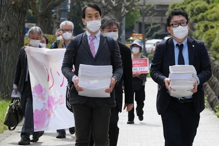 Hiroki Ishiguro (R), a lawyer who has represented technical interns, walks to the Supreme Court in Tokyo to submit an appeal and signed petitions for acquittal of Vietnamese technical intern trainee Le Thi Thuy Linh. Photo: AFP