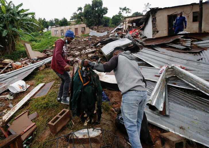 People find their late relative's church uniform in the rubble of a building, which was destroyed during flooding leaving several people dead, at the KwaNdengezi Station, near Durban, South Africa, April 16, 2022. Photo: Reuters