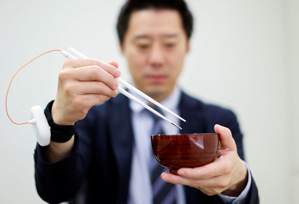 An employee of Kirin Holdings demonstrates chopsticks that can enhance food taste using an electrical stimulation waveform that was jointly developed by the company and Meiji University's School of Science and Technology Professor Homei Miyashita, in Tokyo, Japan April 15, 2022. Photo: Reuters